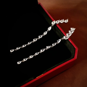 Macro shot of silver drop earrings with pear-cut zircon tassels in a black velvet gift box
