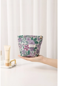 Detail of floral jacquard cosmetic bag with gold flower zipper and brand label