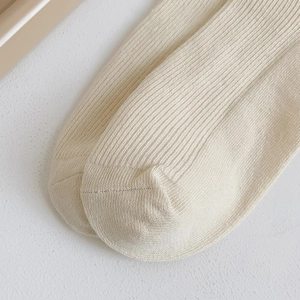 Detailed macro view of cream-colored ribbed cotton knit fabric on sweet style mid-calf socks