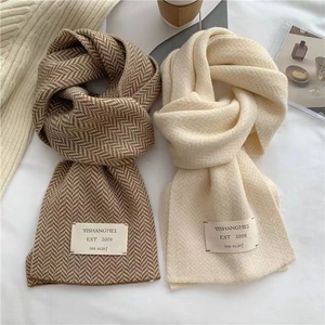 Détail de texture de deux écharpes en maille épaisse marron chevron et blanc crème