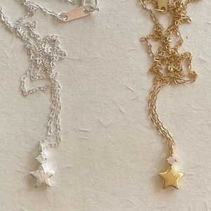 Detail of brushed gold and silver star pendants with tiny zircon on thin chains