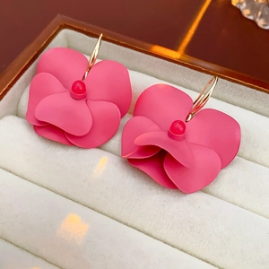Detailed close-up of pink flower earrings with golden hooks in a white velvet jewelry box
