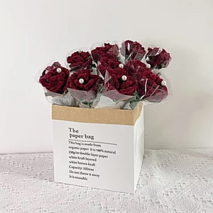 Handcrafted red yarn rose bouquet in organic kraft paper bag with pearl accents