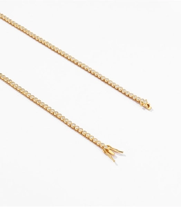 Close-up of golden tennis chain with round zircons and secure double-side safety clasp