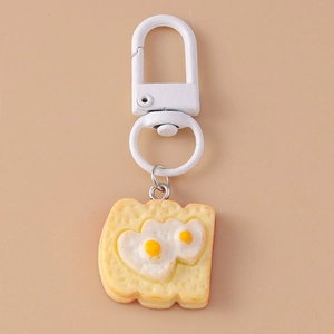 Macro detail of toast keychain with a heart-shaped fried egg on soft beige background