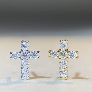 Macro detail of cross stud earrings in silver and gold finishes with moissanite stones