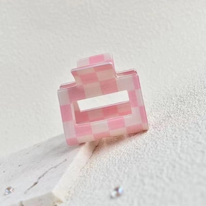 Detail shot of the pink and white checkered hair claw clip on a white stone background
