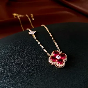 Elegant gold necklace with red gemstone four-leaf flower pendant on a black display stand