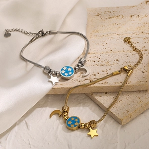 Star and moon charm bracelet in gold and silver finish on a luxury satin background