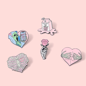 Detail of 5-piece pink skull enamel pins with rose and heart motifs on a pastel background