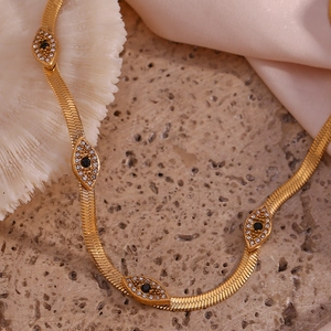 Macro view of gold snake chain necklace with evil eye pendants and sparkling stones