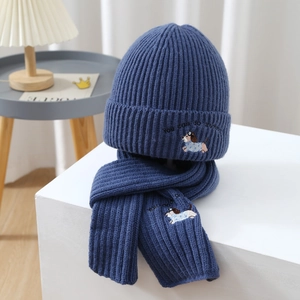 Close-up of knit beanie and scarf set featuring dog embroidery and ribbed texture