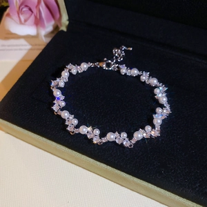 Detail of zircon butterfly bracelet with pearls in black jewelry box and pink flowers