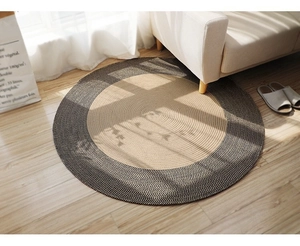 Detailed texture of a round bicolor jute woven rug on light wood flooring with soft shadows