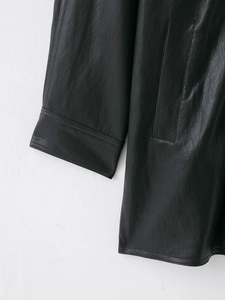 Close-up of black leather jacket cuff and pocket detail showing natural texture