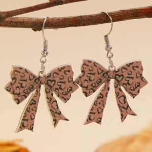 Detail van strik oorbellen met luipaard hartpatroon hangend aan een natuurlijke tak