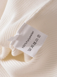 Detailed close-up of white ribbed knit fabric texture and care label with material info