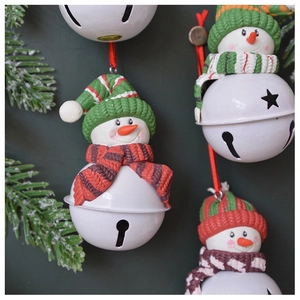 Detail of Christmas snowman bell ornament with knitted hat and festive scarf on pine branches