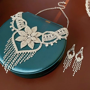 Detailed view of silver crystal flower necklace set with tassel earrings on green box