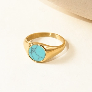 Detailed close-up of a gold signet ring featuring an inlaid round turquoise stone