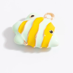 Vue macro d'un pendentif en forme de poisson vert clair et jaune avec cadre doré