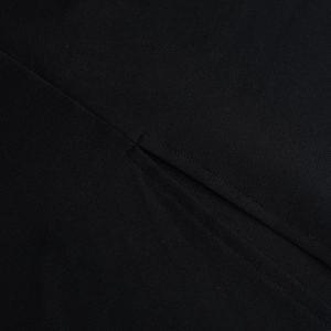 Primer plano detallado de las costuras y volantes del vestido negro de manga larga