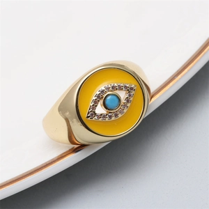 Macro view of gold evil eye ring featuring yellow enamel and a sky blue centerpiece