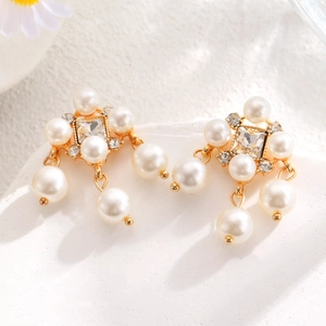 Detail of vintage gold earrings with layered faux pearls and square crystal accents