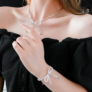 Close-up of elegant silver bow jewelry set worn by a model against black backdrop