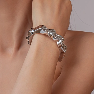 Close-up of a silver irregular liquid metal bangle with a polished fluid lava texture