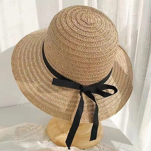 Dettaglio di un cappello di paglia da donna con un classico fiocco in nastro nero.
