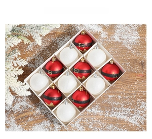 Detail of red and white 6cm Christmas balls with pine branches on snowy wood background