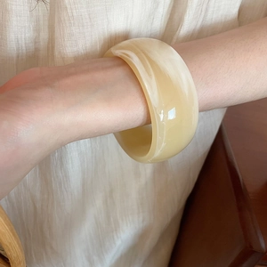 Close-up of cream acrylic bangle with marble texture worn on wrist for a retro look