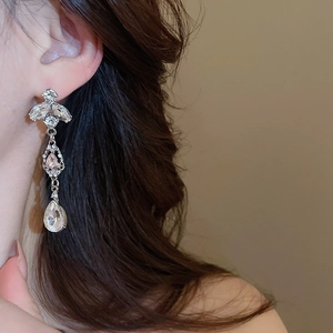 Detail of silver drop earrings with pink crystals and floral tassels on a female model