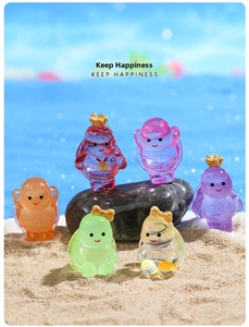 Close-up of six colorful resin turtles with crowns on a sandy beach setting