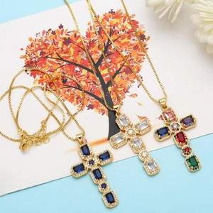Detailed view of three cross necklaces with colorful zircon stones on a designer card