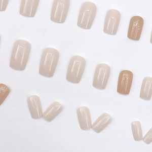 Glossy nude and beige press-on nails set with elegant gold glitter accents on white