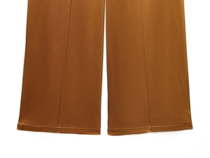 Detailed close-up of brown wide-leg trousers featuring a silky satin glossy finish