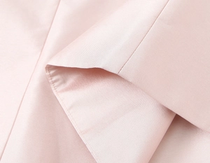 Vue macro du tissu en satin rose lisse montrant les coutures fines et la texture