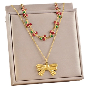 Double-layered gold necklace featuring sweet red cherry charms and a large bow pendant
