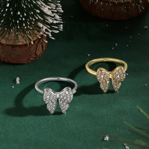 Detail of silver and gold bow rings with clear zircons on festive green background