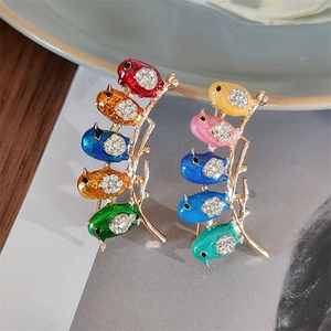 Detailed macro of bird earrings featuring vibrant enamel colors and sparkling crystals
