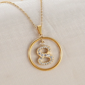 Macro shot of gold necklace with round pendant featuring a zircon-encrusted number 8