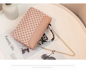 Detail of elegant small square handbag with silk scarf handle and golden chain strap