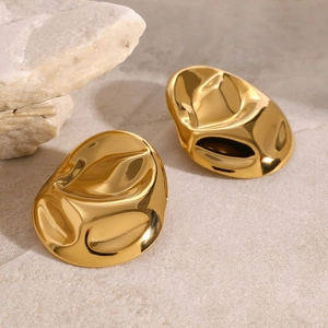 Vintage 18k gold irregular oval hammer texture earrings on beige stone background
