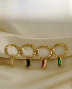 Vue macro de boucles d'oreilles dorées avec breloques en zircon sur tissu de soie