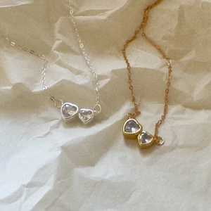 Detailed view of twin heart-shaped zircon pendants on delicate gold and silver necklaces