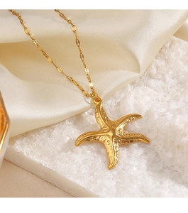 Macro detail of a golden starfish pendant resting on silk fabric and textured stone