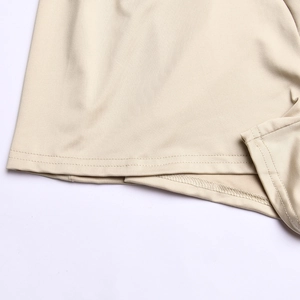 Detailed close-up showing the precise double-needle stitching on the beige romper's hemline
