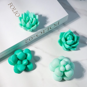 Close-up of four green succulent-shaped resin ornaments on a marble desk background